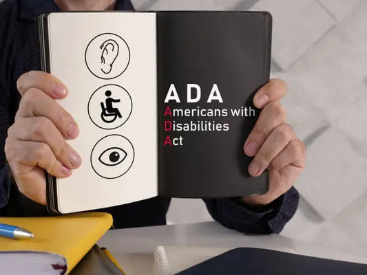 A man holding open a book that has left side visuals of an ear, man/wheelchair and eye. right side says ADA Americans with Disabilities Act